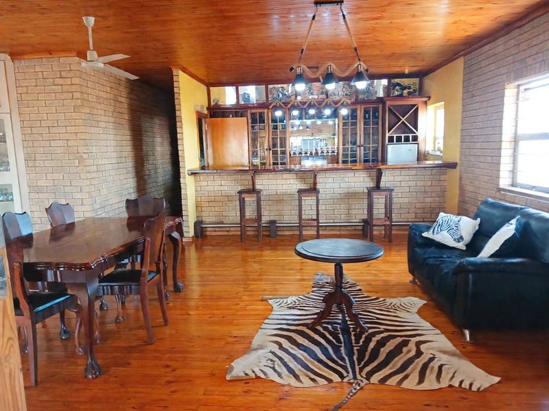 Spacious entertainment area featuring a built-in bar with timber finishes, exposed brick walls, and warm timber flooring, ideal for hosting guests.