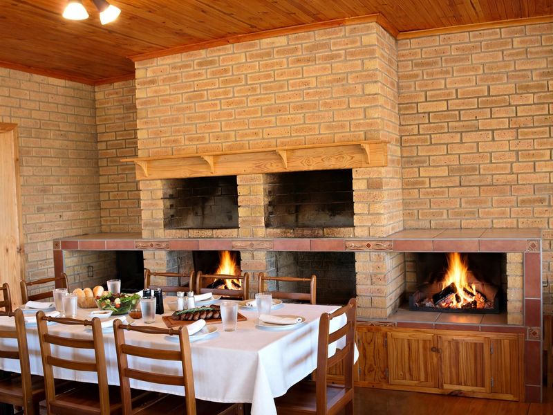 A rustic living area featuring a prominent double brick fireplace with a wooden mantel and integrated cabinetry, creating a warm and inviting atmosphere.