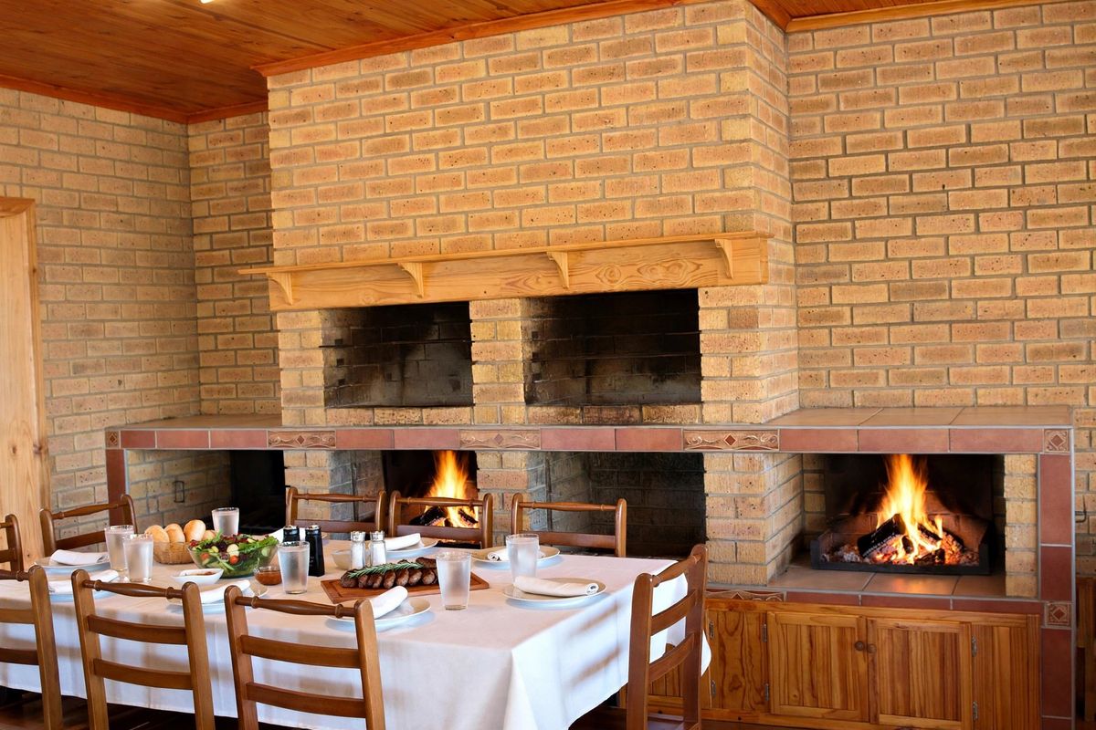 A rustic living area featuring a prominent double brick fireplace with a wooden mantel and integrated cabinetry, creating a warm and inviting atmosphere.