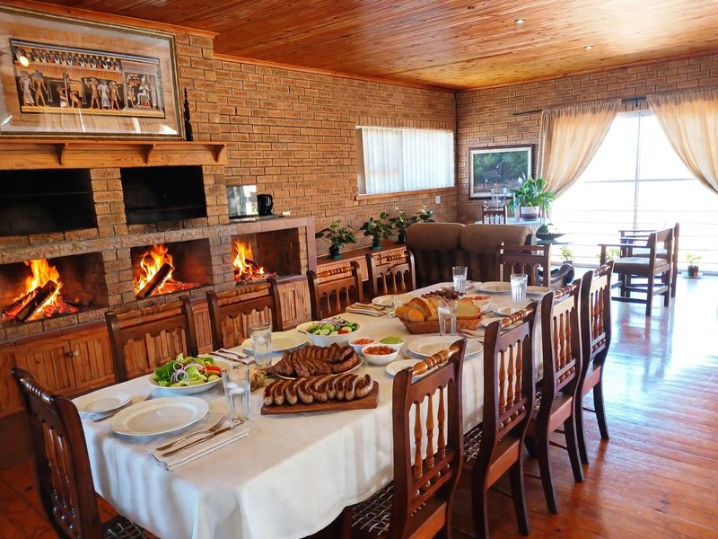 Spacious dining room featuring exposed brick walls, a large built-in double fireplace, warm timber ceiling, and hardwood flooring, creating a cozy and inviting atmosphere.