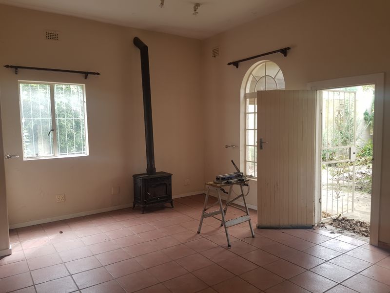 An empty living room featuring tiled flooring, a cast iron fireplace, and direct access to an outdoor area through a security gate.