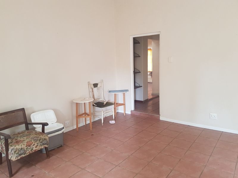An empty living area featuring terracotta-style floor tiles and neutral wall finishes, providing a blank canvas for potential interior design and renovation.