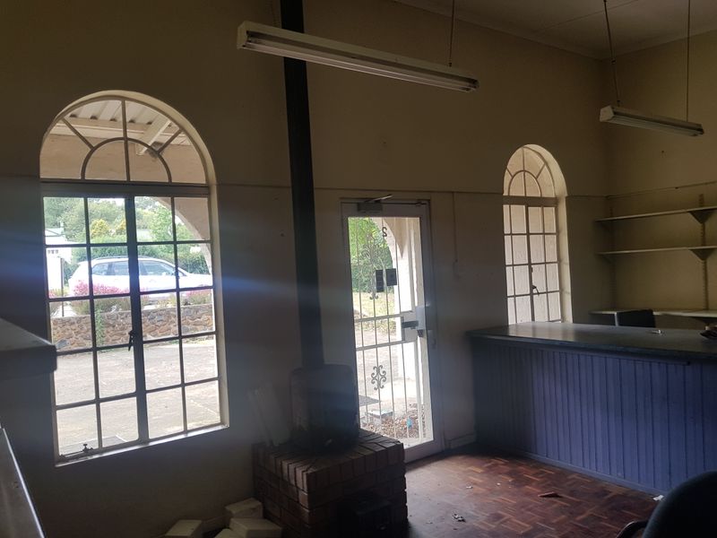 Commercial office space featuring arched windows, a built-in service counter, brick fireplace, and parquet flooring, offering a versatile layout for business use.