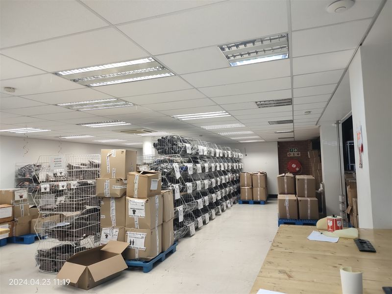 Industrial utility or storage space featuring a suspended ceiling with recessed lighting and exposed brick accents, currently utilized for inventory management.