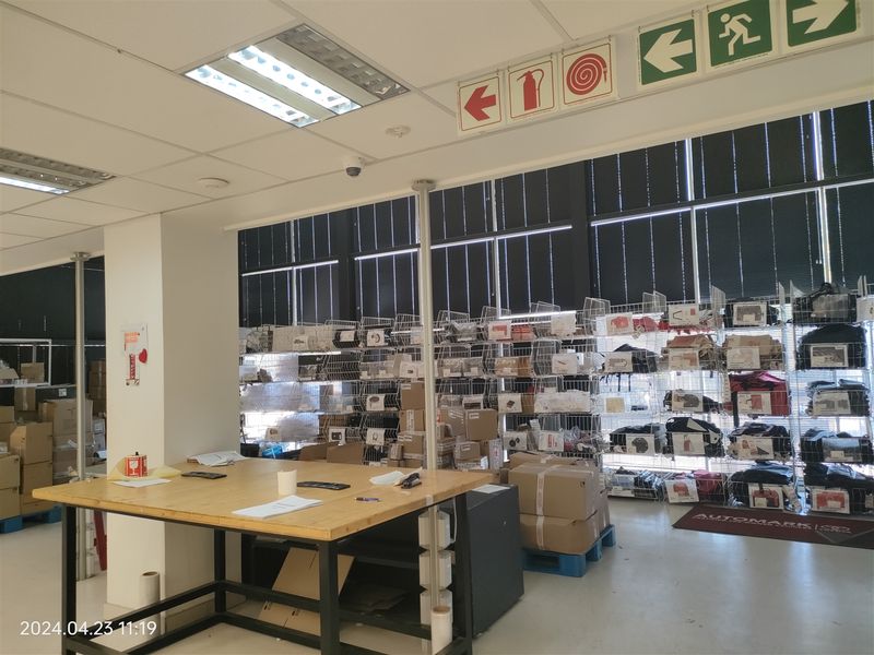 Industrial utility or storage area featuring suspended ceilings, recessed lighting, safety signage, and extensive wall-mounted industrial shelving units.