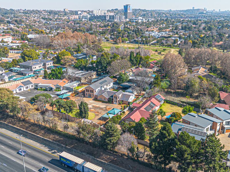 Aerial view of the commercial property complex, showcasing multiple buildings, paved parking areas, and surrounding suburban landscape with highway access.