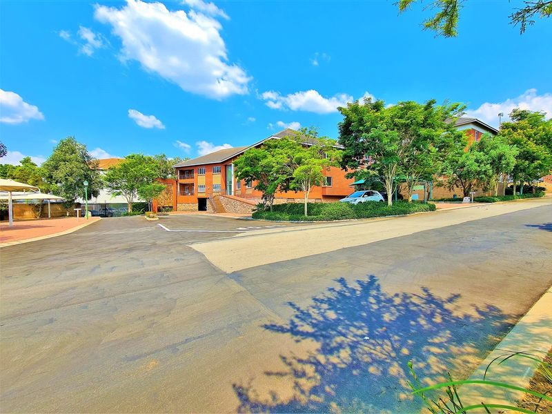 A view of the office building exterior featuring a brick facade, paved driveway, and established landscaping.