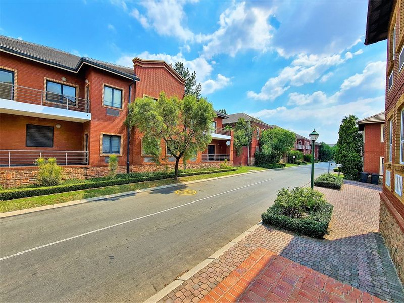 A view of the office complex street frontage featuring red brick architecture, paved driveways, and well-maintained landscaped garden beds.
