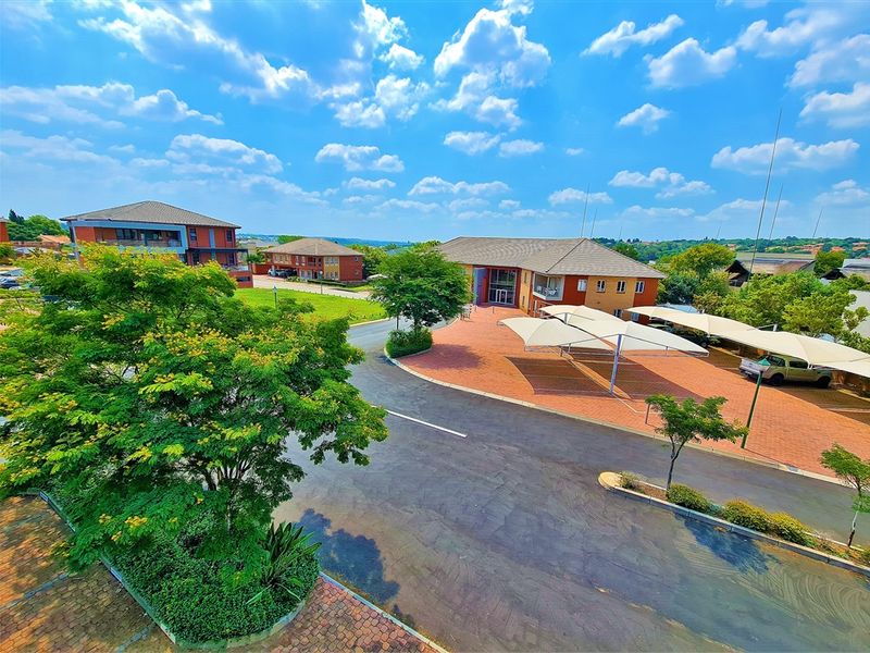 An elevated aerial view of the office park complex, featuring paved driveways, covered parking bays, and well-maintained landscaped grounds.