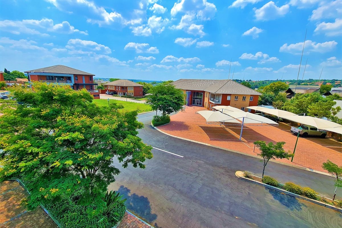 An elevated aerial view of the office park complex, featuring paved driveways, covered parking bays, and well-maintained landscaped grounds.