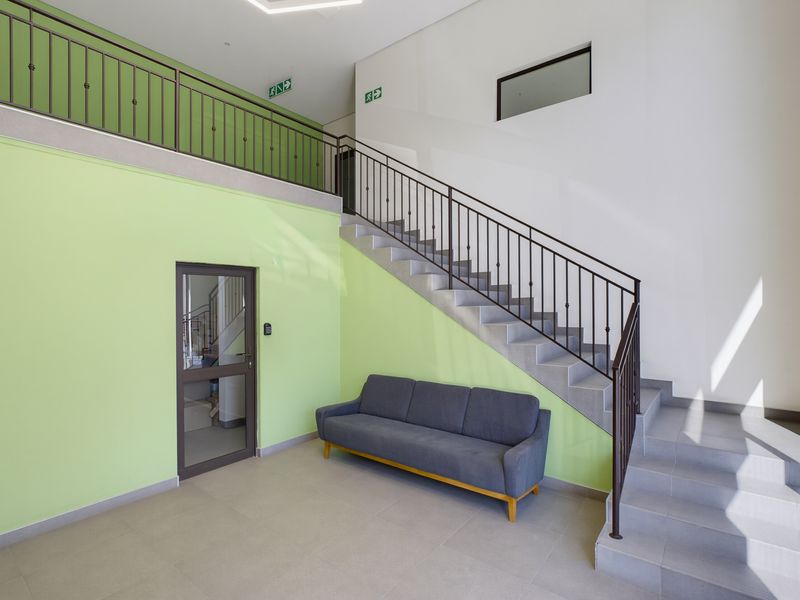 Modern commercial entrance foyer featuring a tiled staircase with wrought iron balustrades and bright green accent walls.