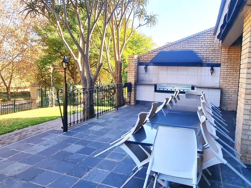 Covered outdoor patio area featuring a built-in braai, tiled flooring, and direct access to the garden.