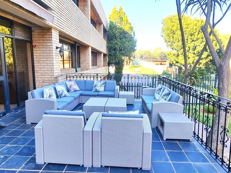 A spacious outdoor patio area featuring dark tiled flooring, wrought iron railings, and direct access to the office building interior.