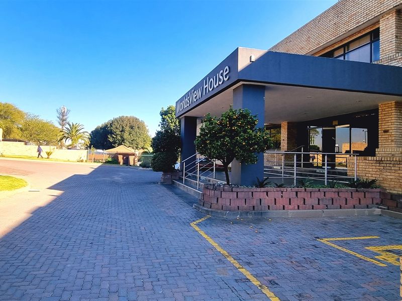 Exterior view of the office building entrance, featuring a paved driveway, covered portico, and designated accessible parking bays.