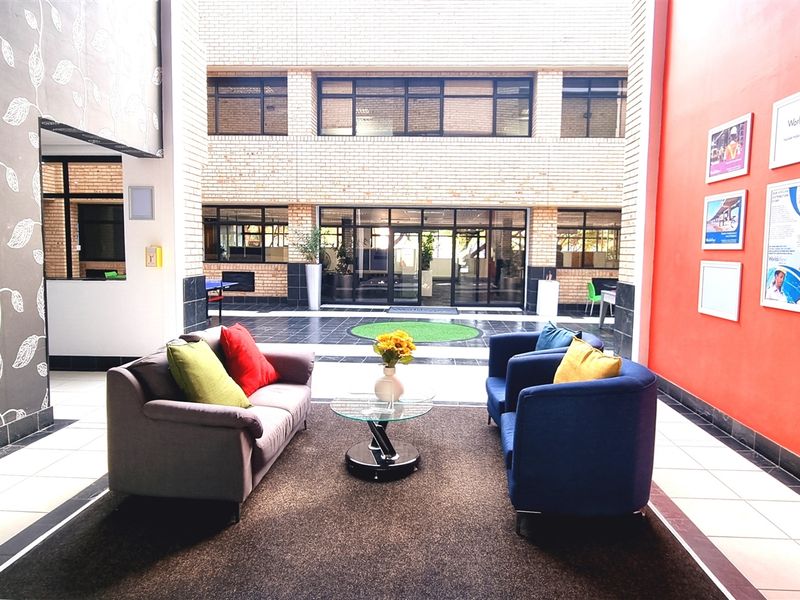 A bright and welcoming office reception area featuring a high-ceiling atrium, tiled flooring, and a vibrant accent wall.