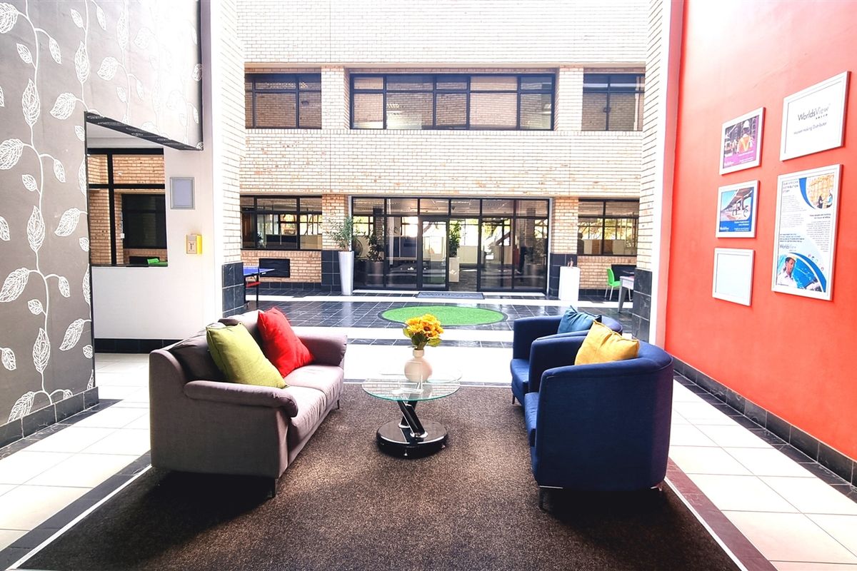A bright and welcoming office reception area featuring a high-ceiling atrium, tiled flooring, and a vibrant accent wall.