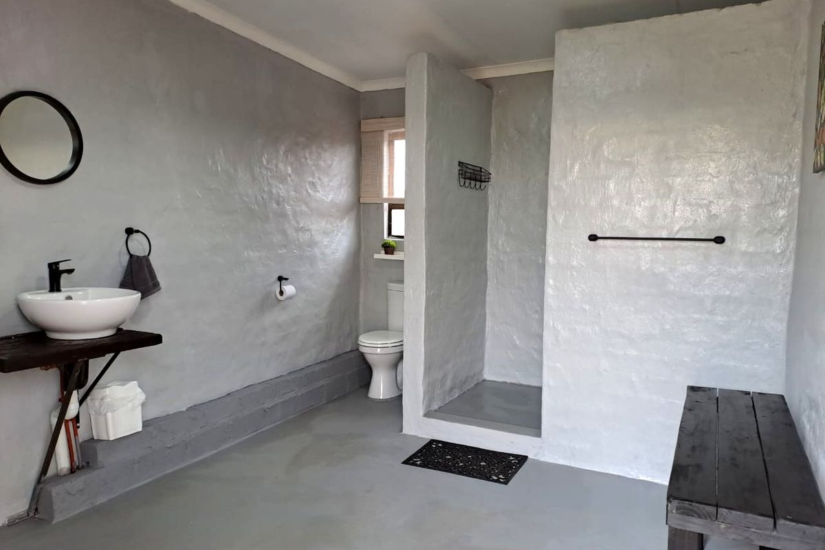 A modern bathroom featuring a vessel sink, walk-in shower, and minimalist grey textured walls with a clean, functional layout.