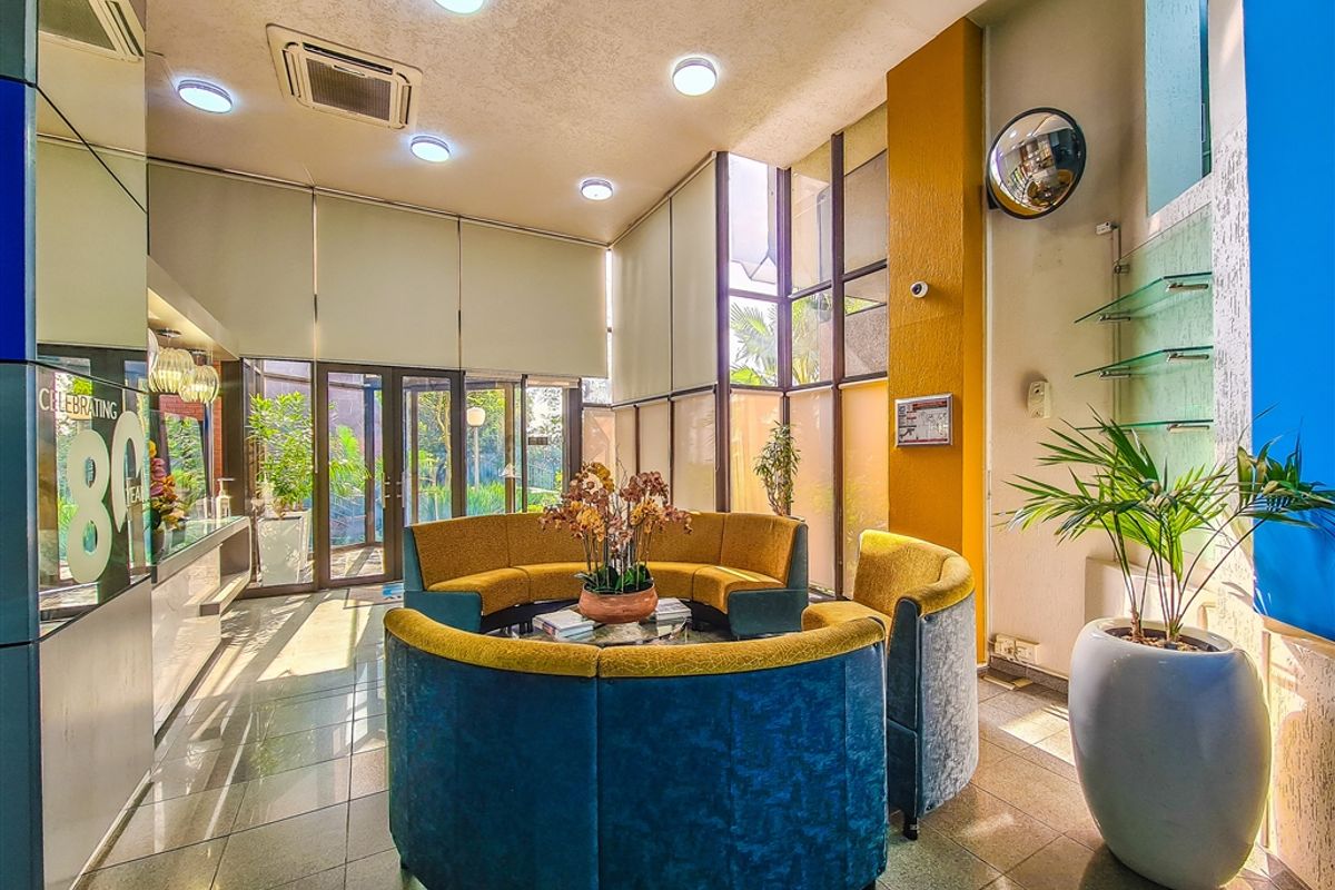 A bright and welcoming office reception area featuring tiled flooring, floor-to-ceiling glass partitions, and integrated recessed lighting.