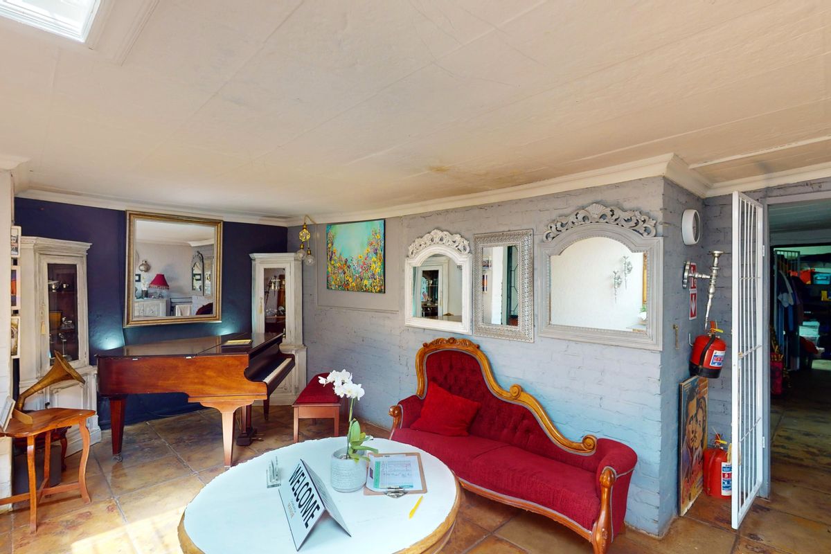 A living area featuring painted brick walls, tiled flooring, and a skylight, with visible water staining on the ceiling.