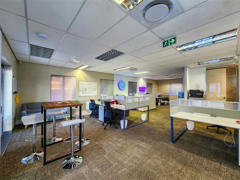 Open-plan office space featuring suspended ceilings, recessed lighting, air conditioning, and integrated workstation partitions with carpeted flooring.
