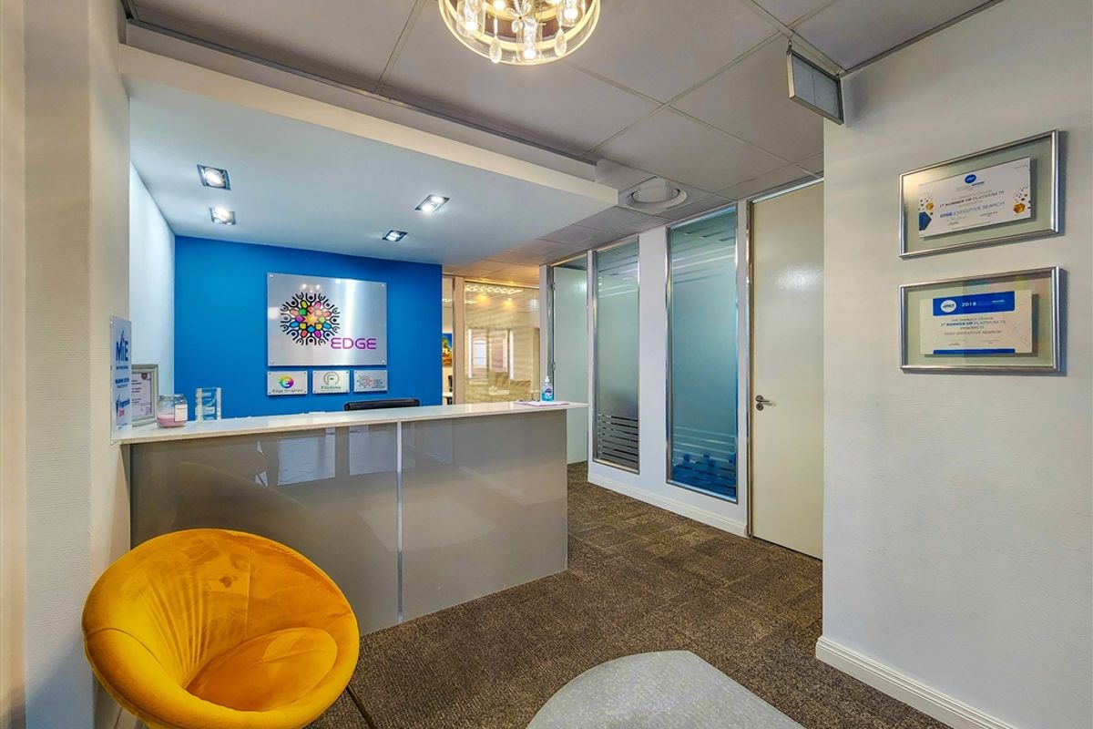 Professional office reception area featuring a modern desk, glass partitions, recessed lighting, and a clean, well-maintained interior finish.