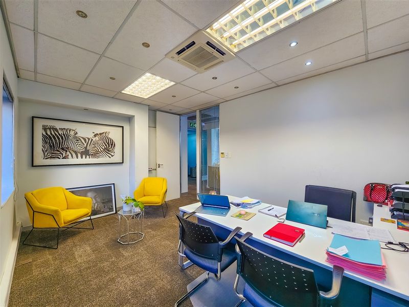 A professional office space featuring a suspended ceiling with recessed lighting, integrated air conditioning, carpeted flooring, and a glass partition wall.
