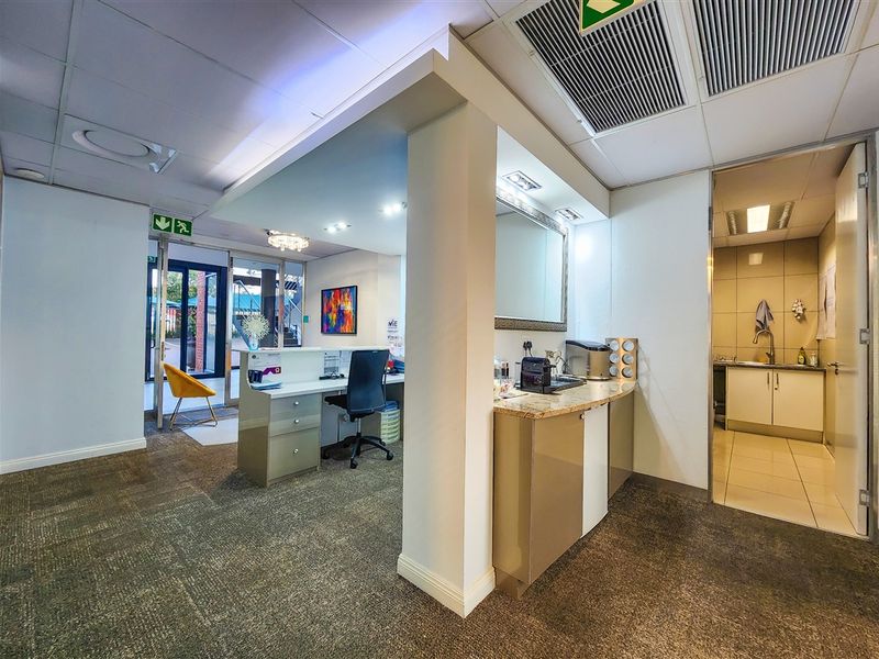 Professional office space featuring a reception area, integrated kitchenette with granite countertops, suspended ceilings with ducted air conditioning, and direct access to a secondary utility room.