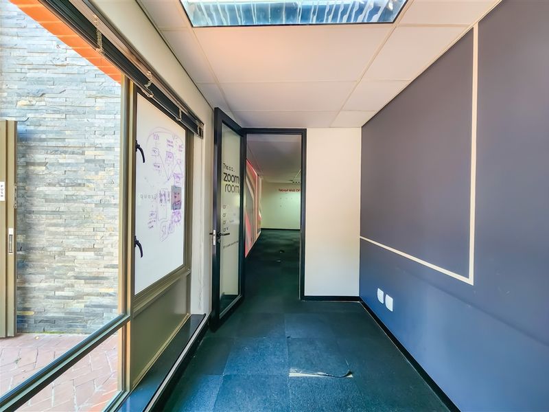 A vacant office space featuring a suspended ceiling, recessed lighting, and a glass door leading to an exterior area with stone cladding.