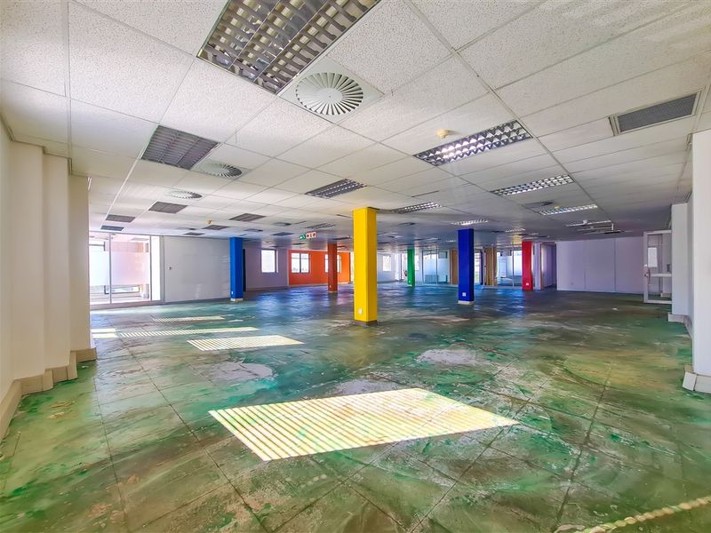 Large open-plan office space featuring a suspended ceiling with recessed lighting, air conditioning vents, and multiple structural columns, requiring floor refurbishment.