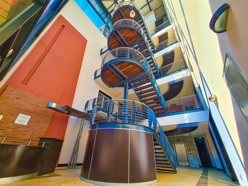 Spacious office building atrium featuring a prominent spiral staircase, high ceilings with skylights, and modern architectural finishes including brick and stone elements.