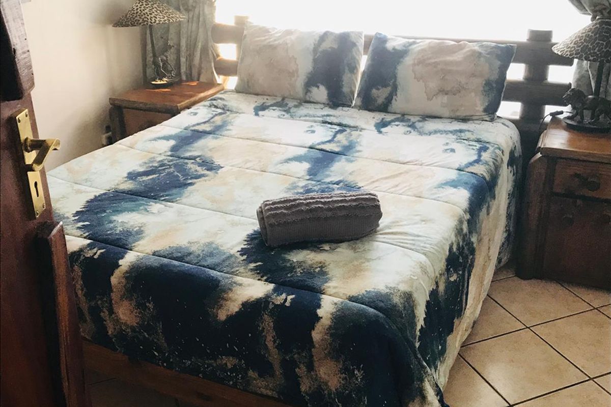 A bedroom featuring tiled flooring and a wooden door frame, presented in a guest house setting.
