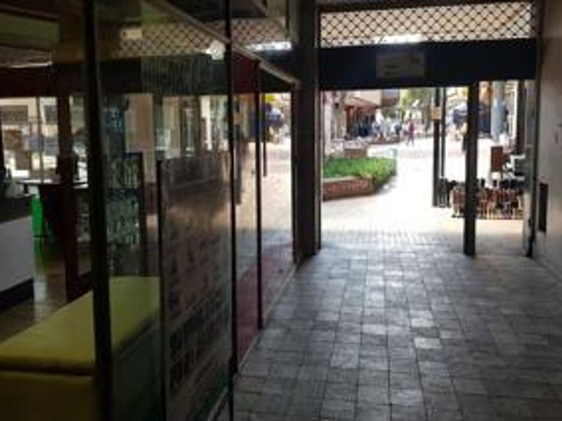 Commercial entrance area featuring tiled flooring and glass storefront access, leading to an outdoor pedestrian walkway.