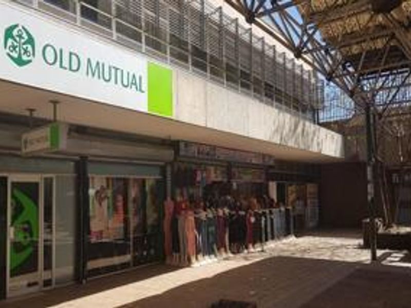 Exterior view of a commercial retail frontage featuring large signage, glass storefronts, and a covered pedestrian walkway.