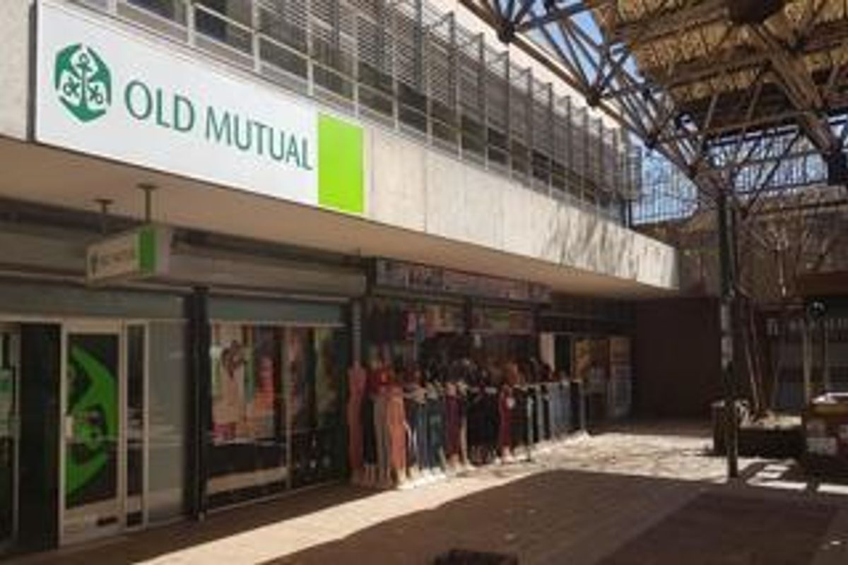 Exterior view of a commercial retail frontage featuring large signage, glass storefronts, and a covered pedestrian walkway.