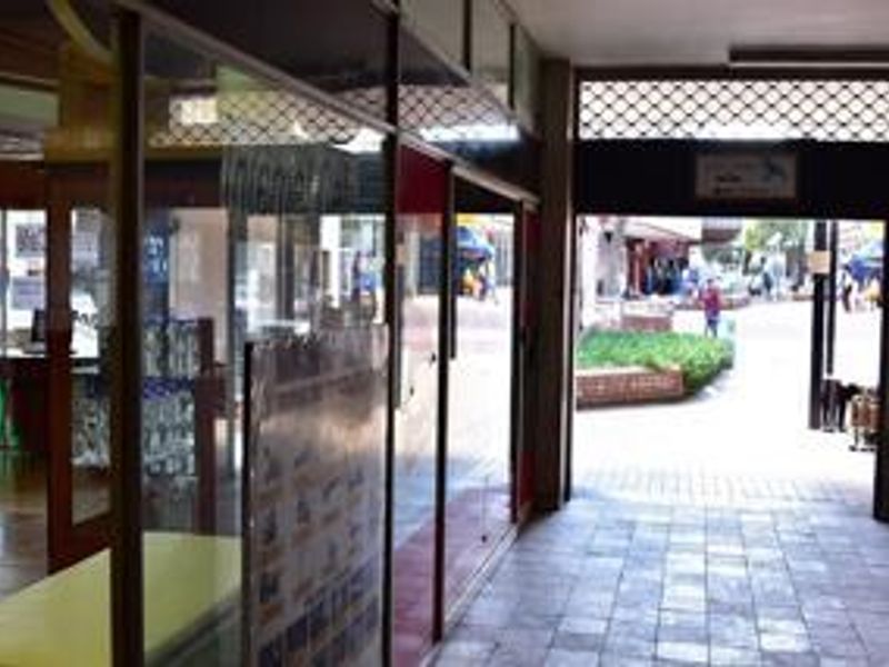 Commercial storefront entrance featuring glass display windows and tiled flooring, providing direct access to an outdoor pedestrian walkway.
