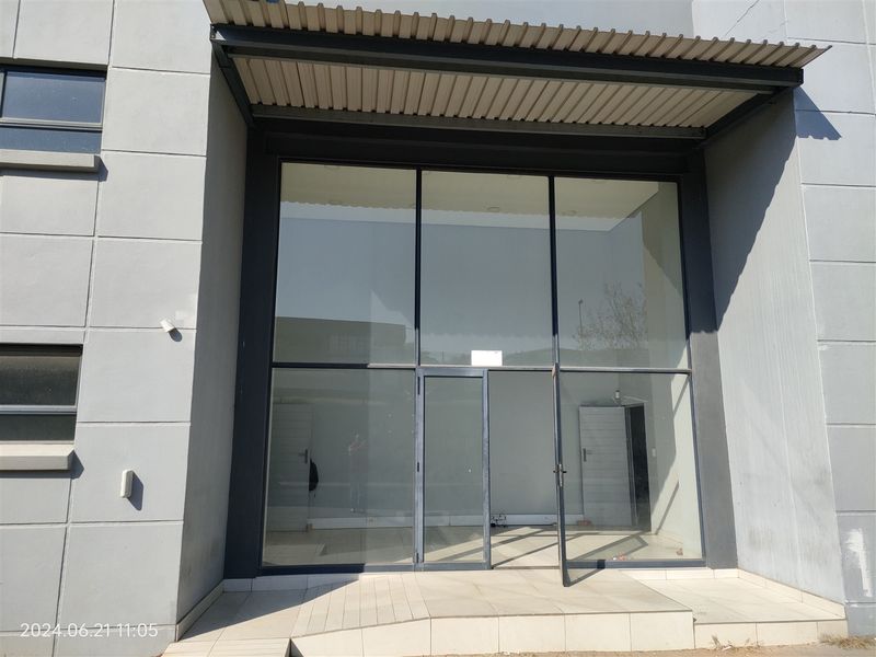 Modern industrial storefront entrance featuring a large glass facade, metal awning, and tiled entry step, providing a professional and clean exterior appearance.
