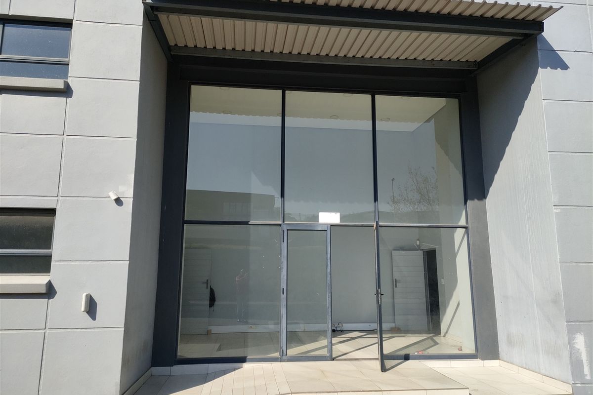 Modern industrial storefront entrance featuring a large glass facade, metal awning, and tiled entry step, providing a professional and clean exterior appearance.