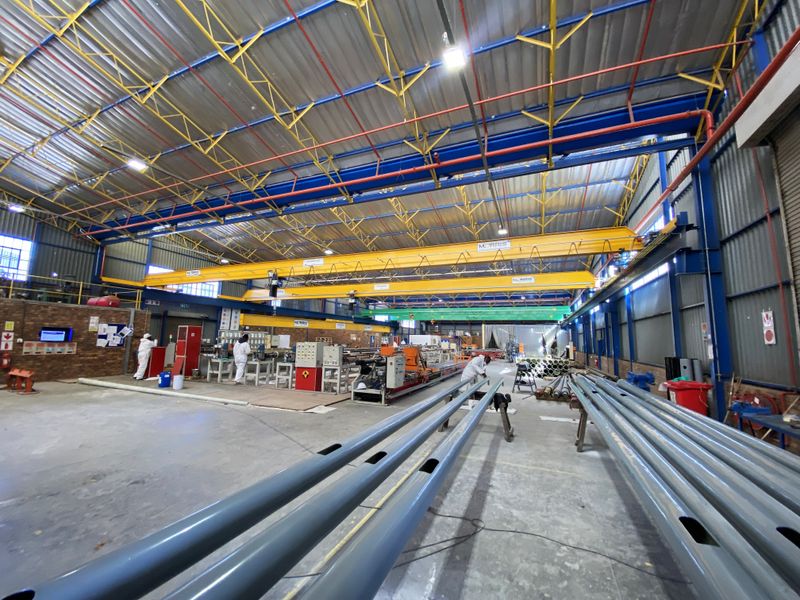 Spacious industrial warehouse facility featuring high-clearance ceilings, overhead gantry cranes, durable concrete flooring, and exposed steel structural elements suitable for manufacturing or storage operations.