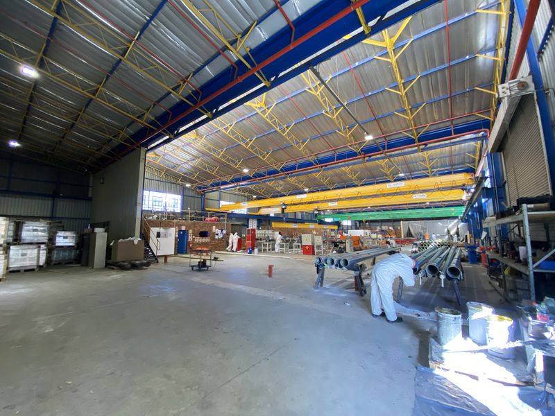 Spacious industrial warehouse facility featuring high-clearance steel truss roofing, overhead crane system, and durable concrete flooring suitable for manufacturing or storage operations.