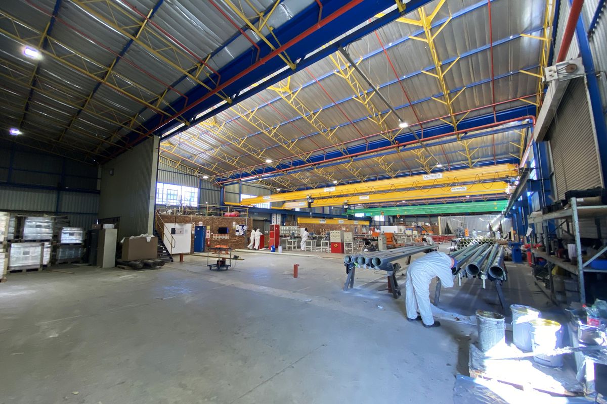 Spacious industrial warehouse facility featuring high-clearance steel truss roofing, overhead crane system, and durable concrete flooring suitable for manufacturing or storage operations.