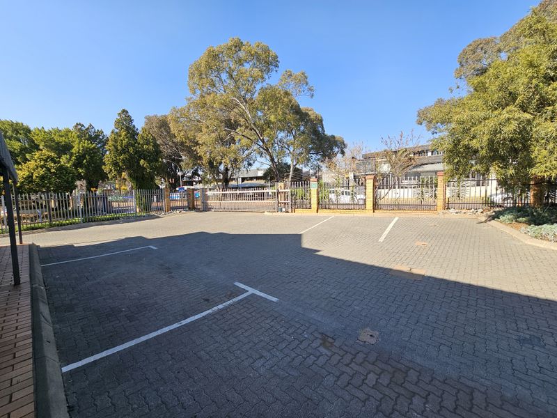 A paved industrial parking area featuring secure steel palisade fencing and a gated entrance.
