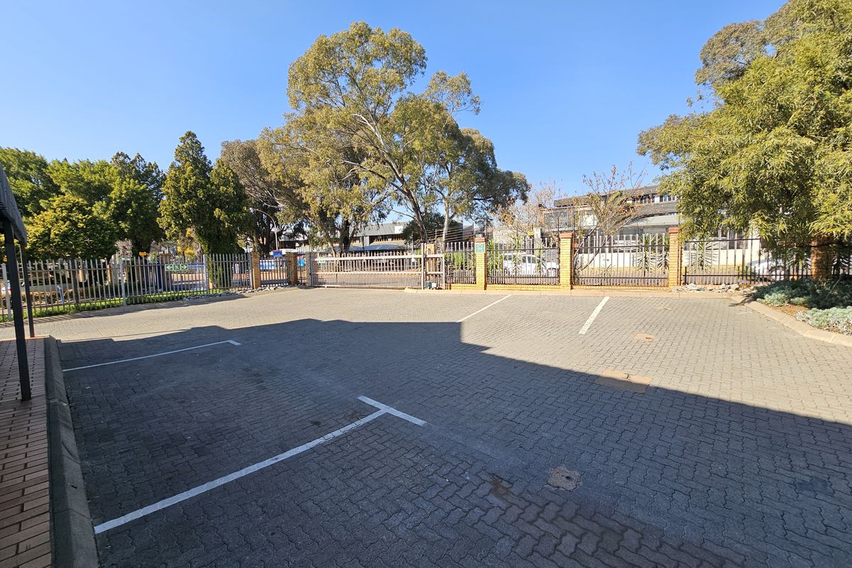 A paved industrial parking area featuring secure steel palisade fencing and a gated entrance.