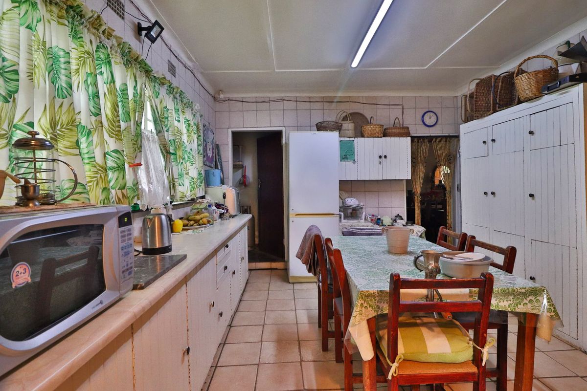 A dated kitchen featuring tiled flooring, wall-to-wall cabinetry, and built-in pantry storage, offering significant potential for a modern renovation.