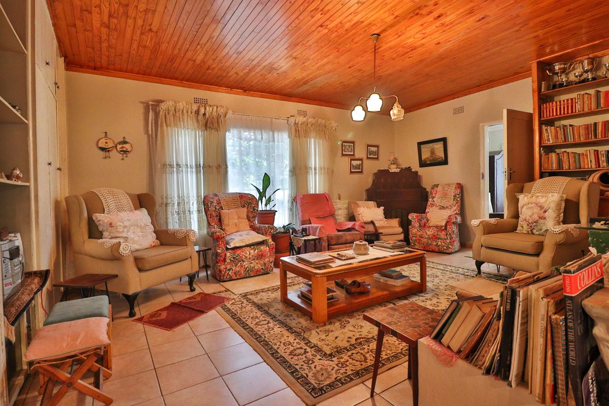 A traditional living room featuring a warm timber tongue and groove ceiling, tiled flooring, and built-in shelving units.