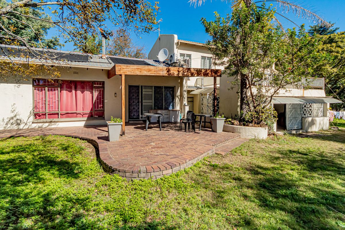 Rear view of the office property featuring a paved patio area, timber pergola, and established garden surroundings.