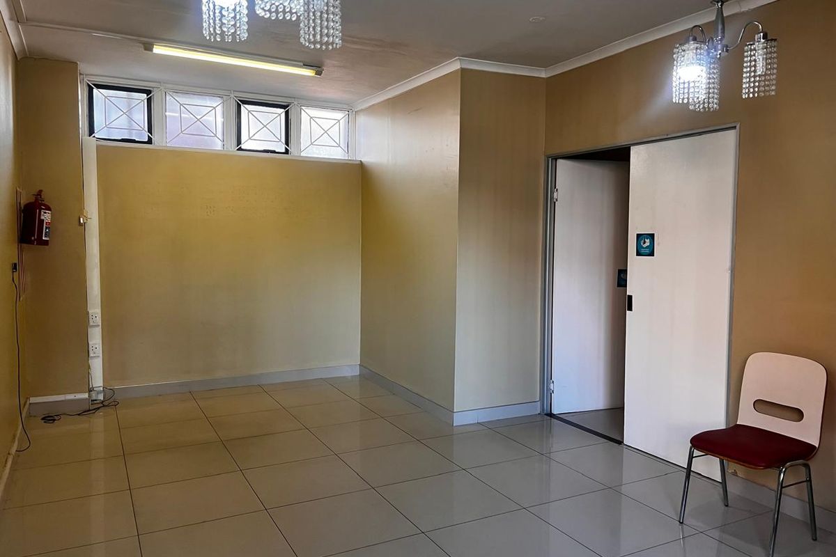 An empty, open-plan retail space featuring tiled flooring, crystal chandeliers, and high-level windows, suitable for a variety of commercial uses.