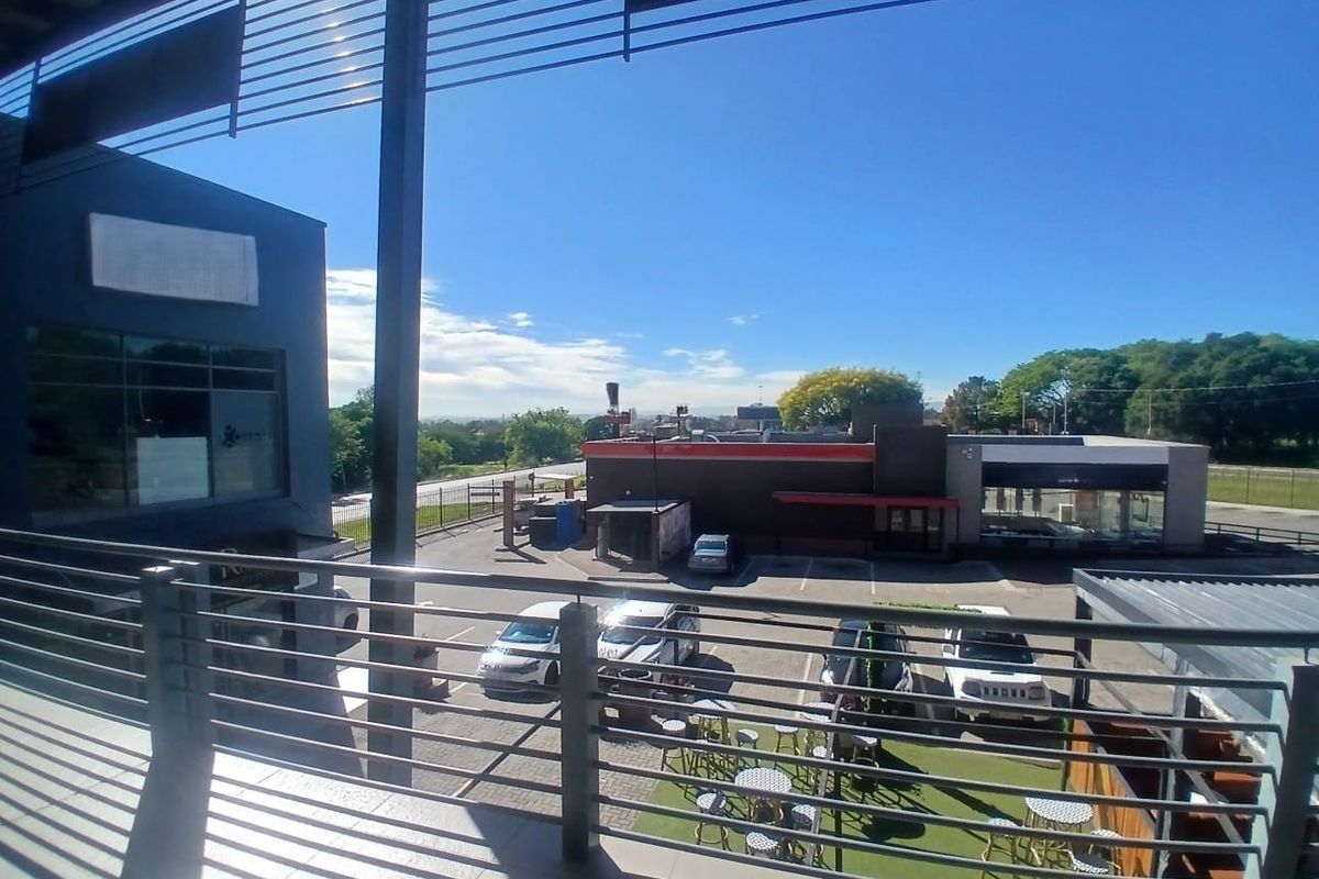 Elevated balcony area with metal railings overlooking the office park parking lot and surrounding commercial area.