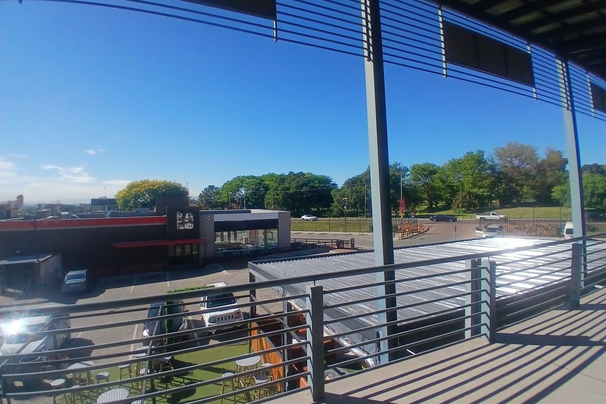 A spacious covered balcony with metal balustrades, offering an elevated view of the surrounding office park and parking area.