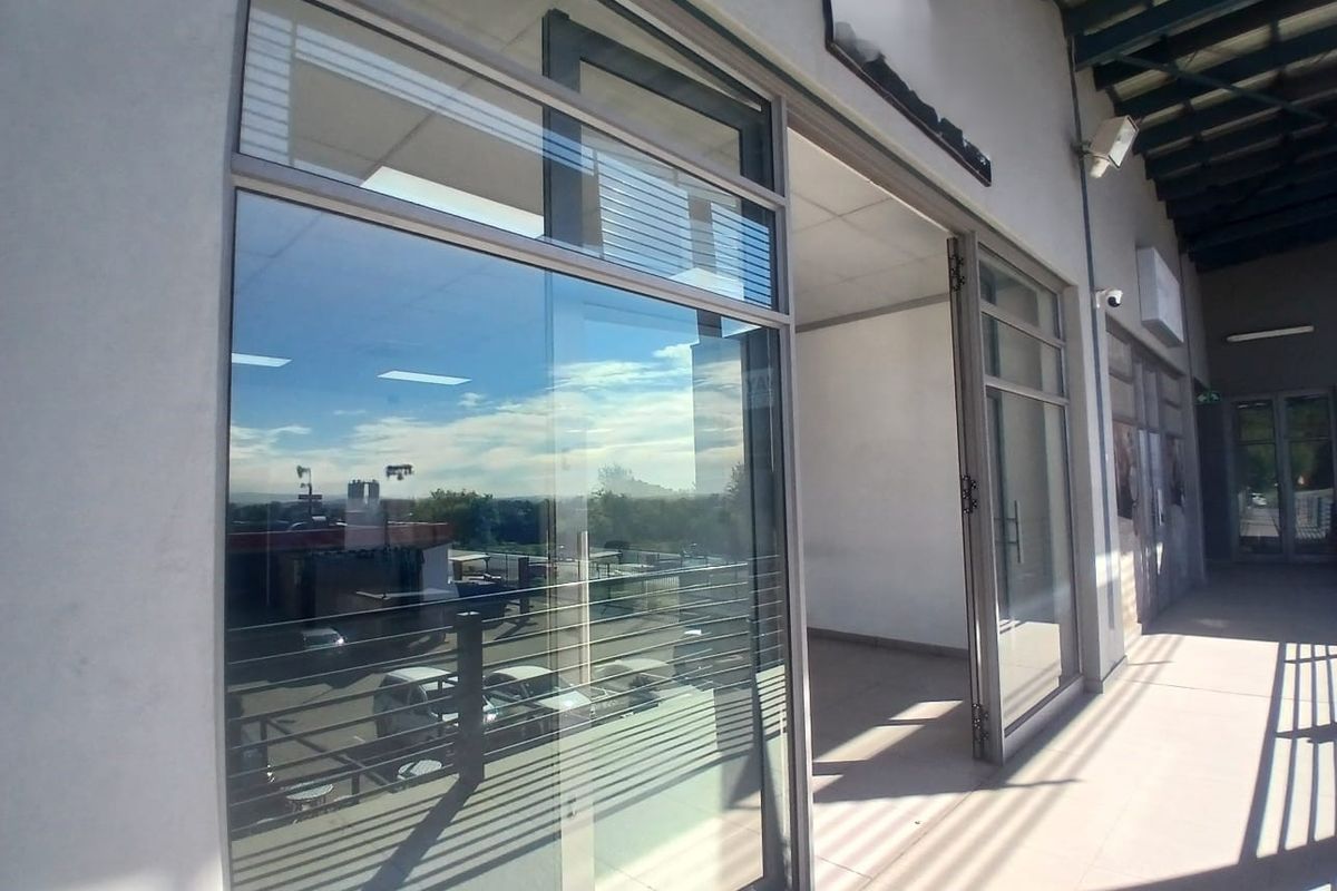 Exterior view of a modern office storefront featuring large glass windows, aluminum framing, and a covered walkway entrance.