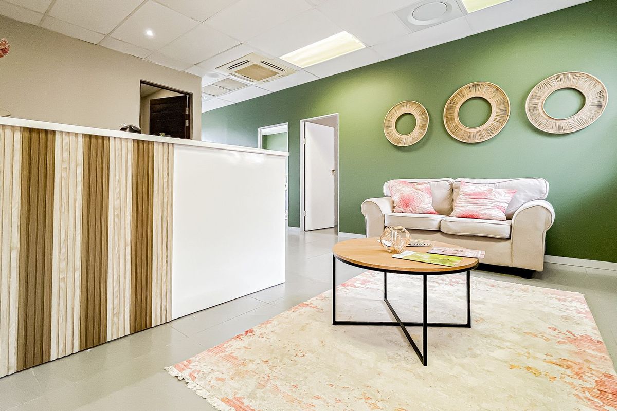 A professional office reception area featuring a modern reception desk, suspended ceiling with integrated lighting, and a comfortable waiting space.